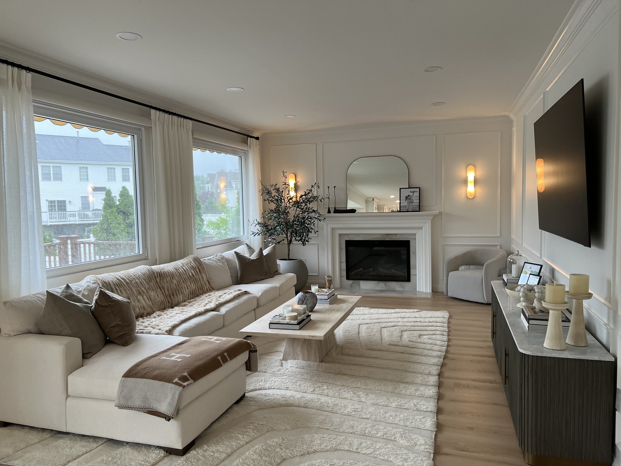 Living room with cream sectional, marble fireplace, and warm sconce lighting