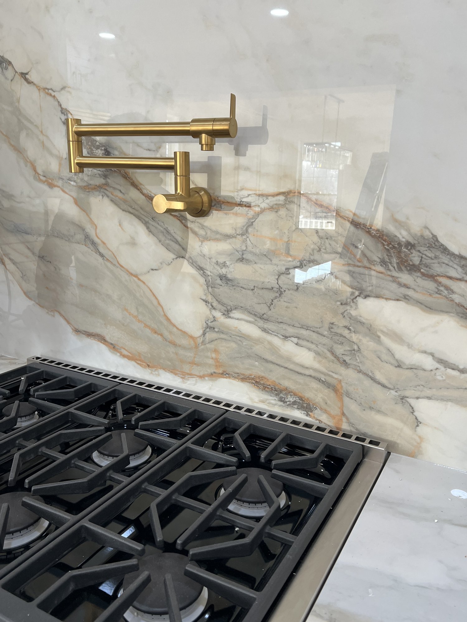 Kitchen backsplash detail with quartzite slab and brass pot filler