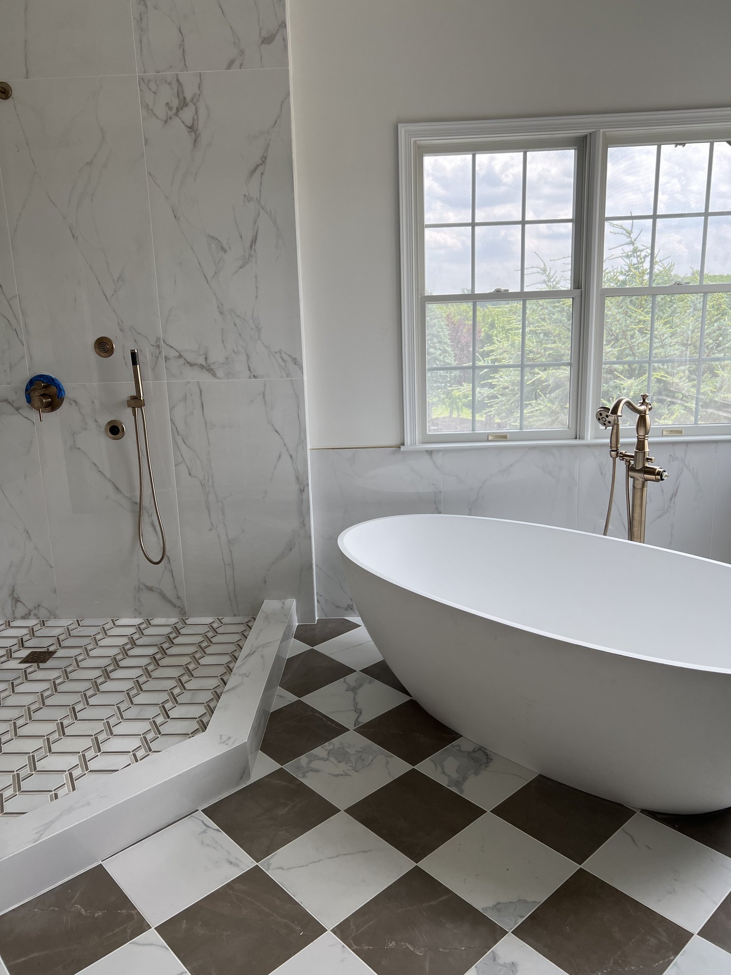 Bathroom with freestanding tub, diamond tile floor, and marble walls